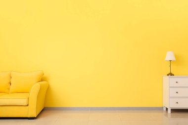 Oda duvarının yanında rahat bir kanepe ve çekmeceler.