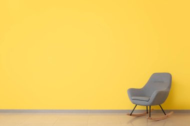 Sallanan sandalye odanın renk duvarının yanında.