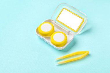 Renk arkaplanında kontak lens ve cımbızla konteyner