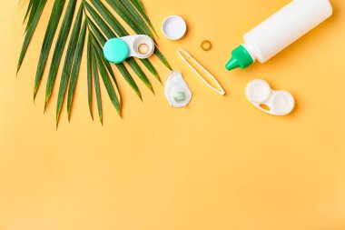 Renk arkaplan üzerinde kontak lens, çözüm ve cımbız içeren kaplar