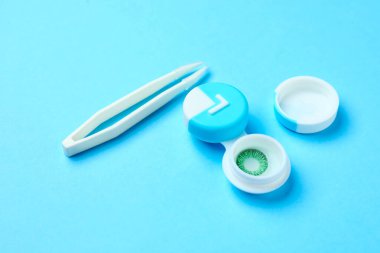 Renk arkaplanında kontak lens ve cımbızla konteyner