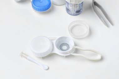 Beyaz arkaplanda kontakt lens ve cımbızla konteyner