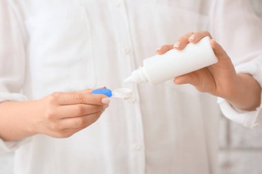 Kadın konteynıra kontak lensli solüsyon dolduruyor, yakın plan.