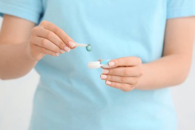 Kontak lens ve konteynırla cımbız tutan kadın, yakın plan.