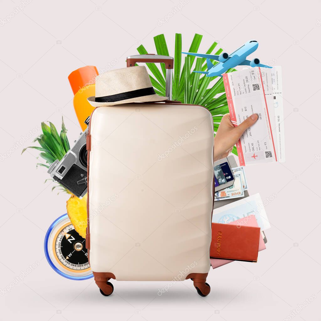 Suitcase with different travel accessories on light background