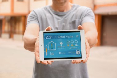 Tablet bilgisayarda akıllı ev otomasyonu uygulaması kullanan bir adam