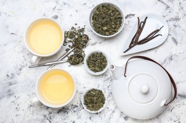 Bir fincan sıcak aromatik çay ve masanda kuru çay yaprakları.