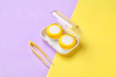 Renk arkaplanında kontak lens ve cımbızla konteyner