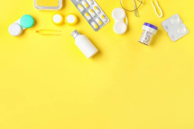 Renk arkaplanında kontak lens, hap ve çözeltiye sahip kaplar