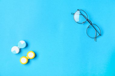 Renk arkaplanında kontak lens ve gözlüklü kaplar