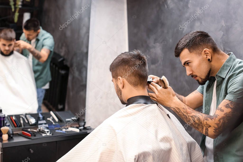 Professional hairdresser working with client in barbershop