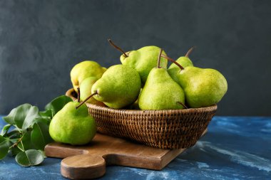 Masada taze olgun armutlarla dolu bir hasır kase.