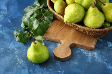 Masada taze olgun armutlarla dolu bir hasır kase.