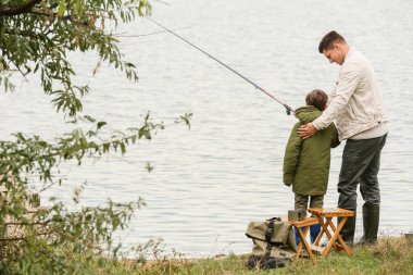 Küçük çocuk ve babası nehirde balık tutuyor.