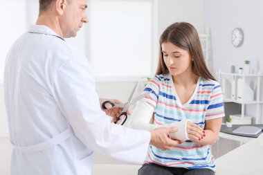 Doktor klinikte genç bir kadının kolundan alçı çıkartacak.