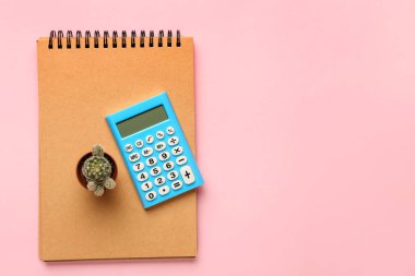 Renk arkaplanı üzerine dijital hesap makinesi, defter ve kaktüs