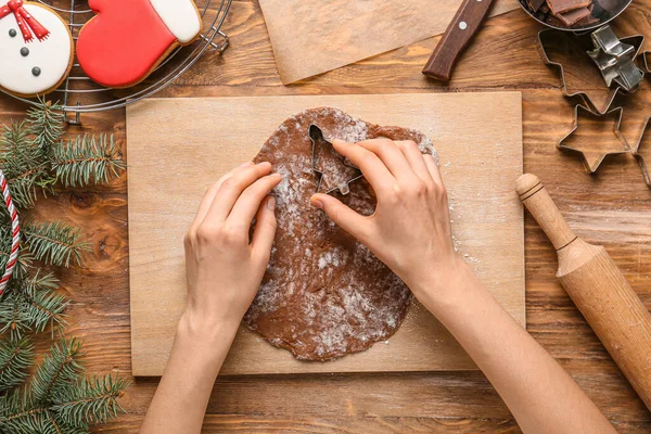 Woman preparing Christmas bakery on table, top view