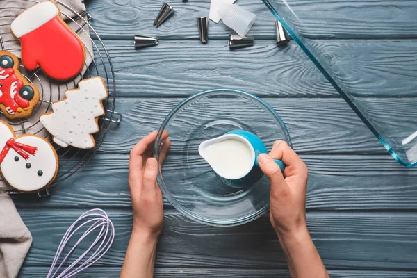 Woman preparing Christmas bakery on table, top view