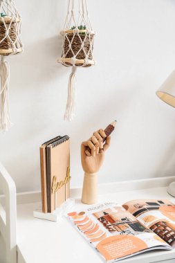 Odanın iç tarafında masa üzerinde tahta bir el ve kalem.