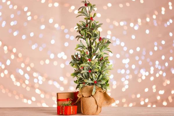 Beautiful mistletoe plant and gifts against blurred lights