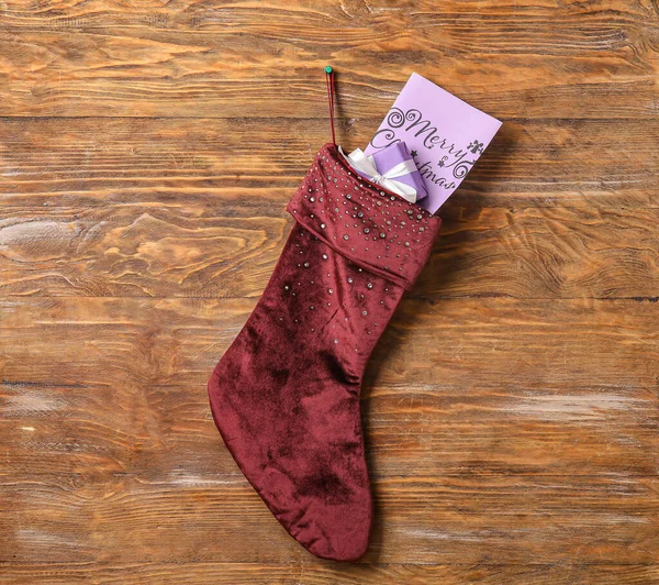 Christmas sock with gifts on wooden background