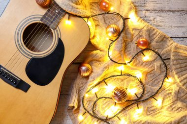 Noel dekoru ve ahşap arka planda süveteri olan gitar.