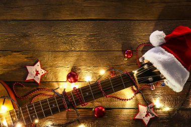 Gitar Noel Baba şapkası ve Noel dekoru ahşap arka planda.