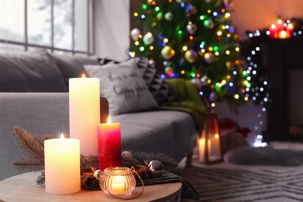 Burning candles in living room decorated for Christmas