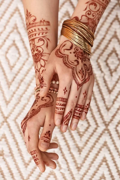 Beautiful female hands with henna tattoo on light background