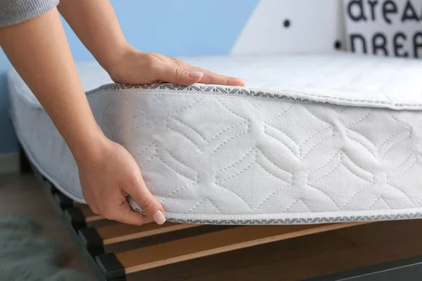 Woman putting soft orthopedic mattress on bed