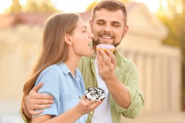 Genç çift dışarıda tatlı çörekler yiyor.