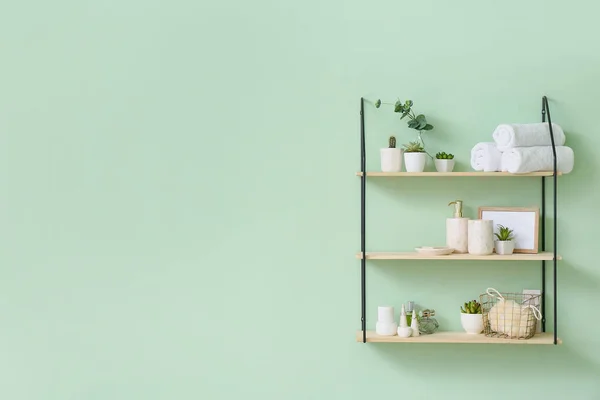 Shelf with bath accessories on color wall