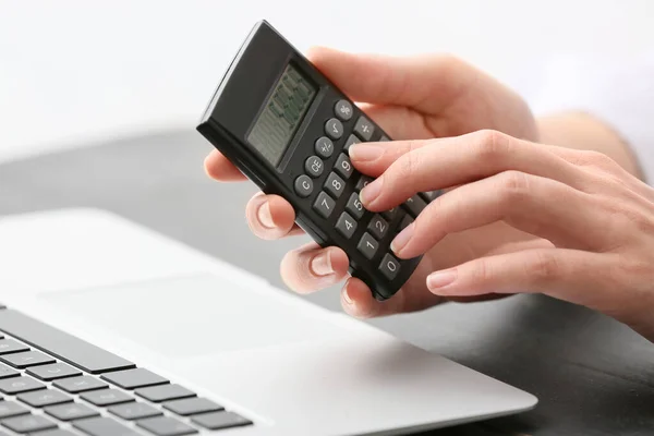 Female accountant with calculator and laptop working in office, closeup