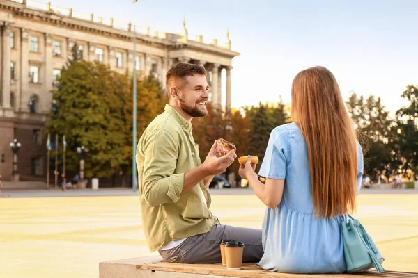 Young Couple Eating Sweet Donuts Outdoors — Stock Photo, Image