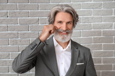 Tuğla arka planda resmi takım elbiseli olgun bir adam