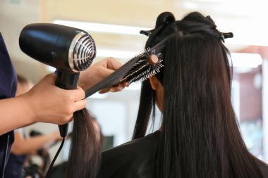 Bayan kuaför müşteriyle kuaförde çalışıyor.