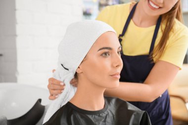 Bayan kuaför müşteriyle kuaförde çalışıyor.