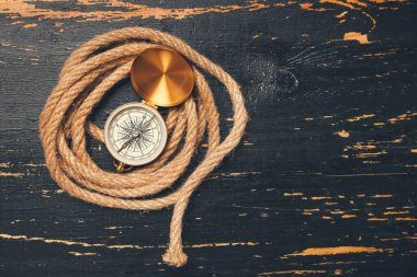 Koyu ahşap arka planda yuvarlak ip ve klasik pusula.