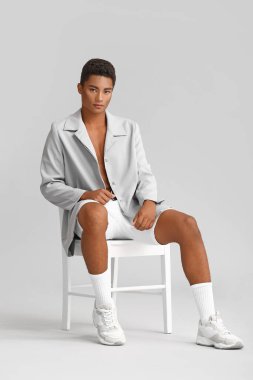 Beyaz arka planda oturan şık genç Afro-Amerikalı adam.