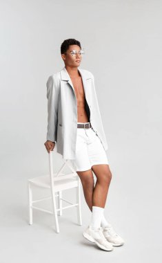 Hafif arka planda sandalyesi olan şık bir Afro-Amerikalı.