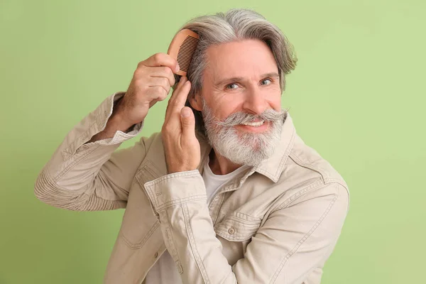 Зрелый Мужчина Расчесывает Волосы Цветном Фоне — стоковое фото