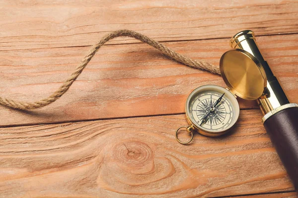 İp, dürbün ve ahşap arka planda klasik pusula.