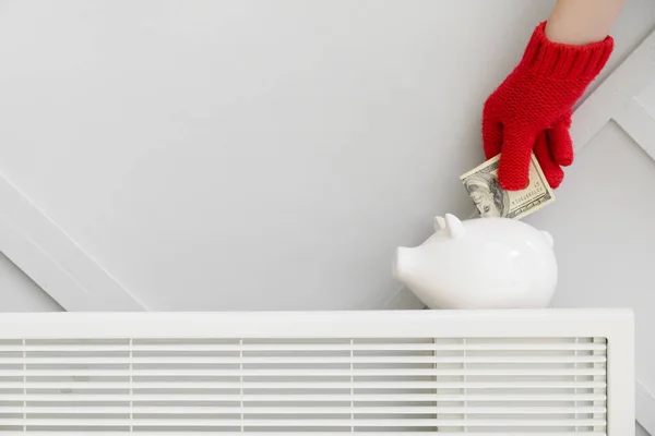 Woman Putting Money Piggy Bank Radiator Concept Heating Season — Stock Photo, Image