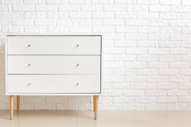 Odadaki tuğla duvarın yanındaki modern çekmeceler.