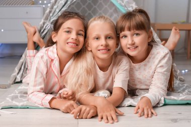 Mutlu küçük kızlar yatak odasında yerde yatıyor.
