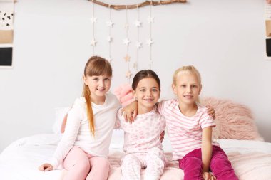 Evde pijamalarıyla oturan tatlı küçük kızlar.