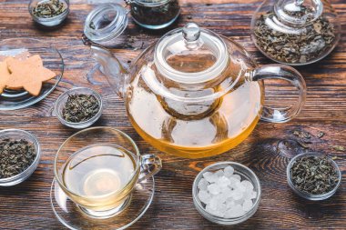 Composition with cup of green tea, teapot and dry leaves on wooden background
