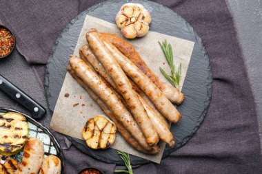 Lezzetli ızgara sosis ve koyu arkaplanda sarımsak tabağı.