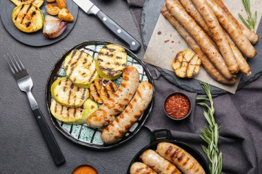 Lezzetli ızgara sosis ve koyu arkaplanda sebze tabağı.