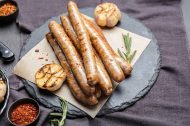 Lezzetli ızgara sosis ve koyu arkaplanda sarımsak tabağı.